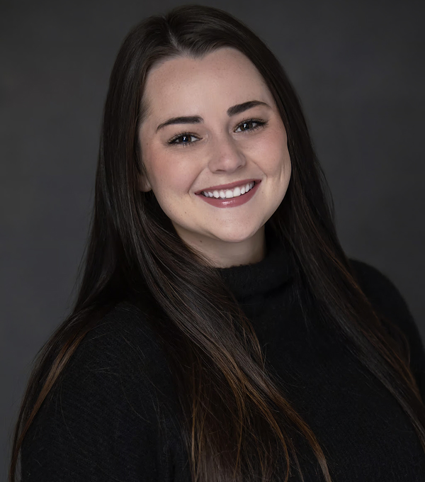 Young woman smiling, looking at camera in professional studio headshot.