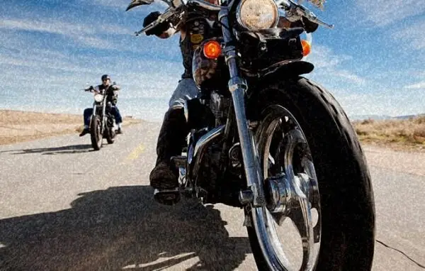 Motorcyclists riding on a desert road, one in foreground, sunny day | Motorcycle accidents.